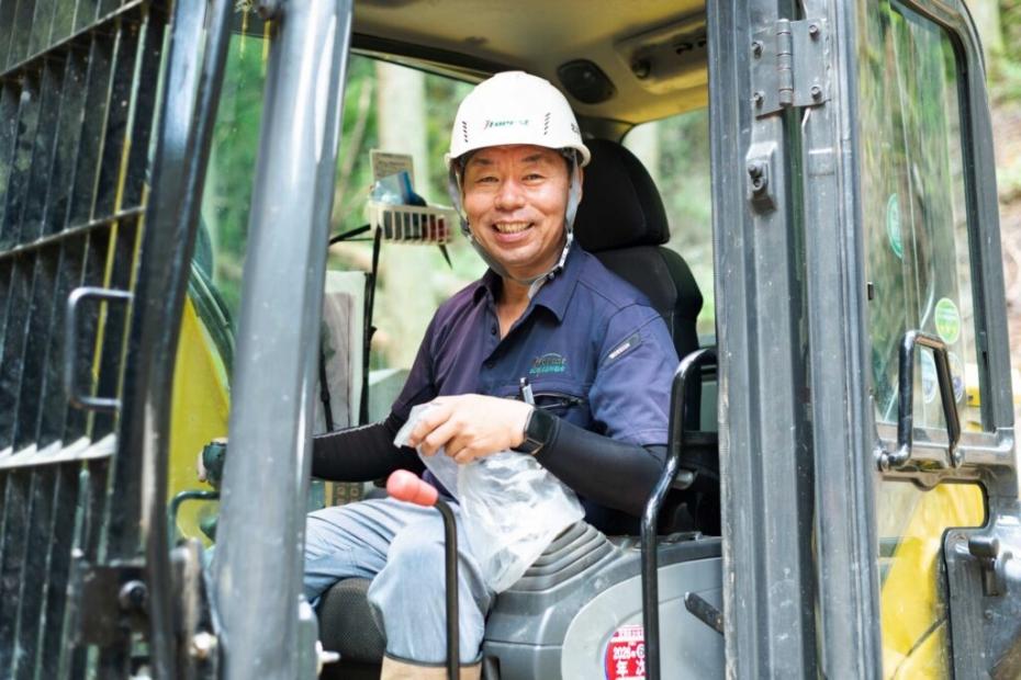 林業用重機に乗って笑顔を向ける藤田さん